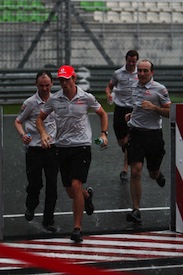 Jenson Button and his McLaren engineers run for cover as a downpour strikes Sepang